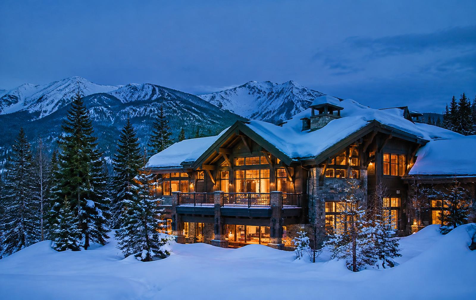 Snow-covered mountain house glowing at blue hour